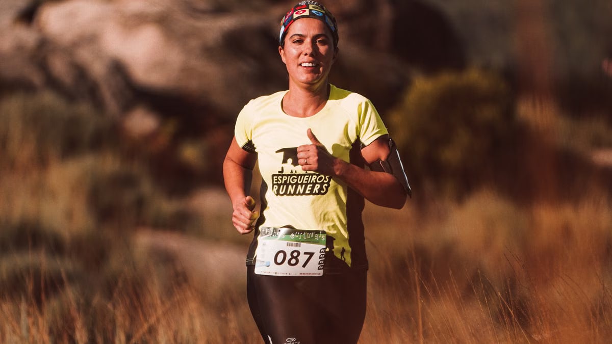 Woman runner in a bright yellow shirt smiling during an outdoor marathon race.